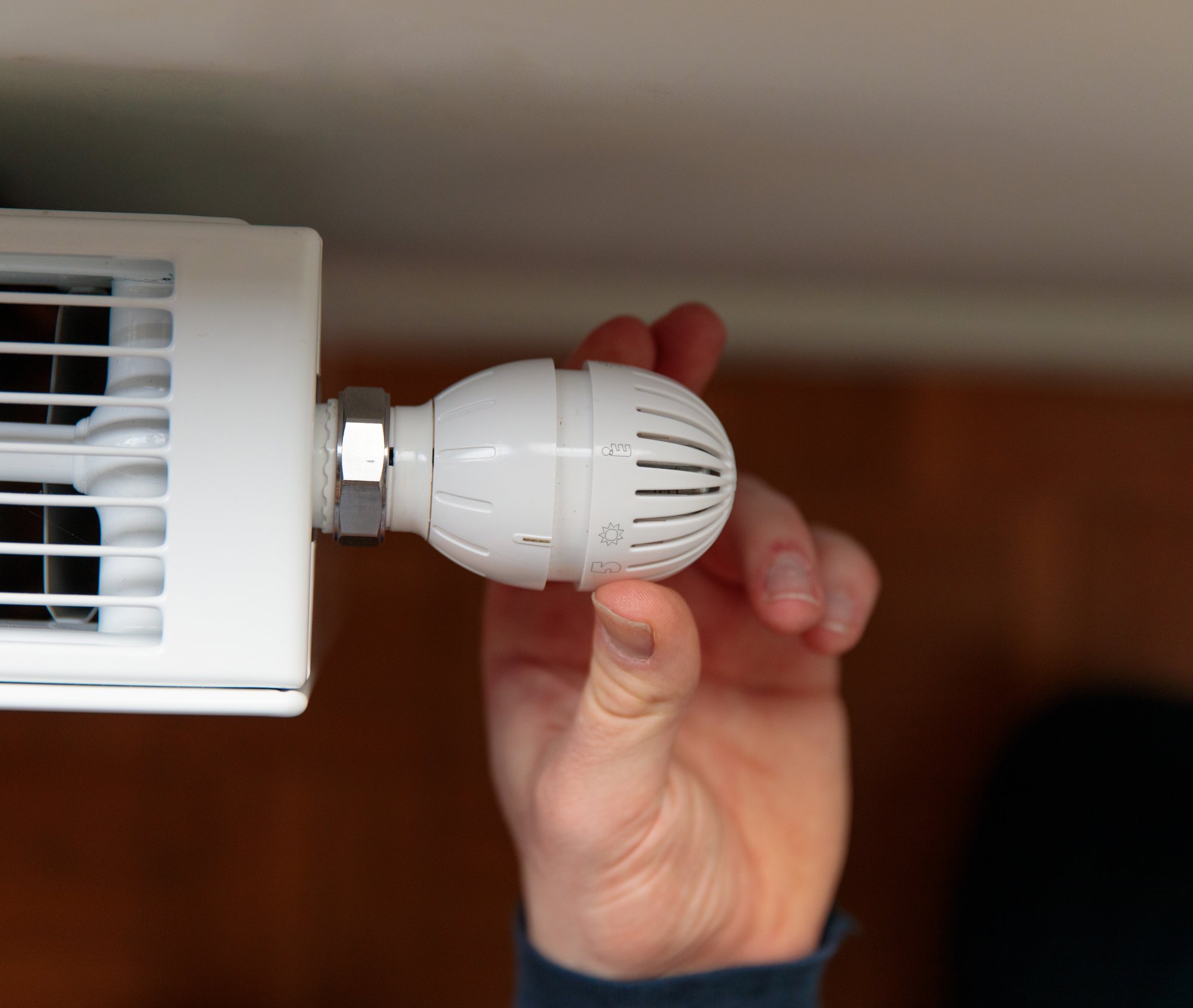 Hand draait aan een thermostatische radiatorkraan