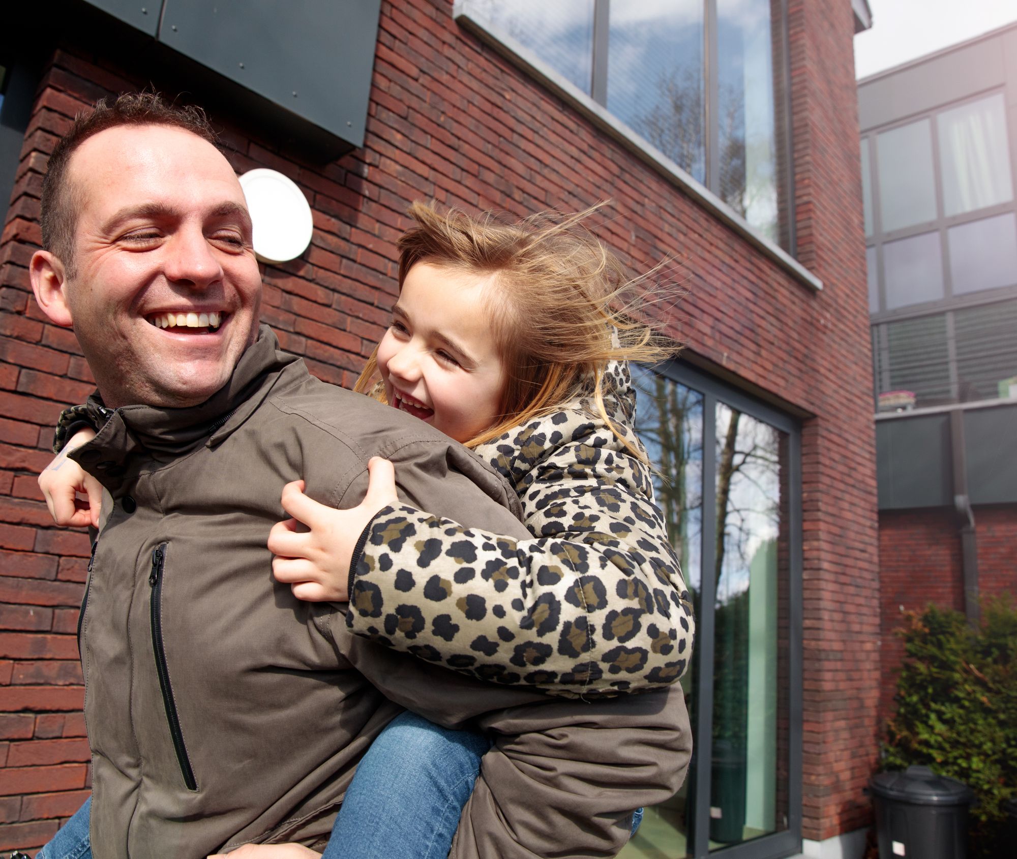 stekr-mijn-verbouwlening Vader met dochter op de rug voor hun woning