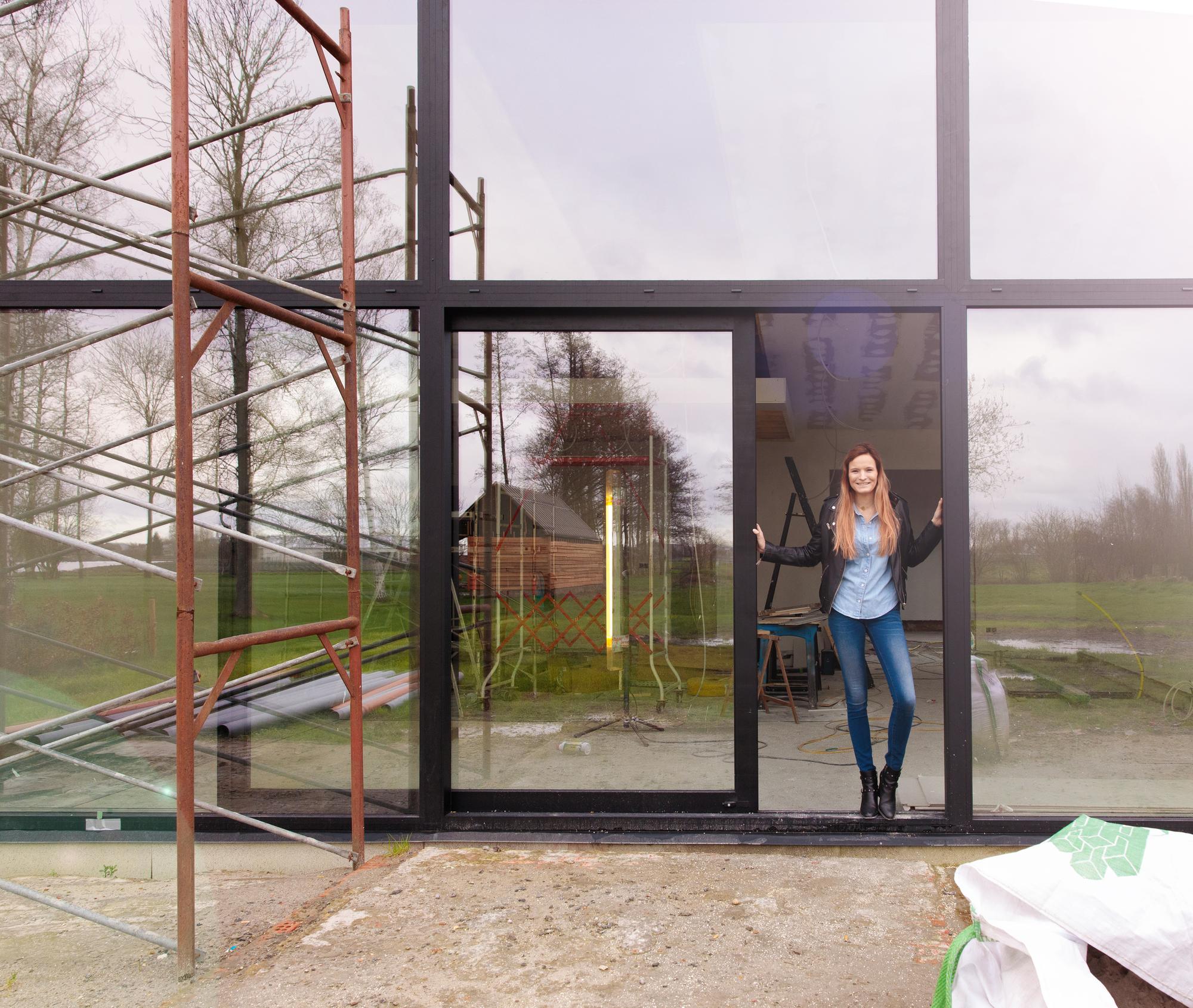 stekr-vind-een-bouwprofessional Vrouw in de deuropening van een woning in renovatie met stelling